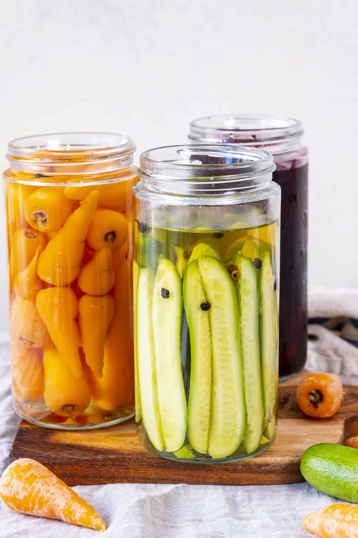木板上的罐子里装着腌黄瓜、胡萝卜和甜菜。