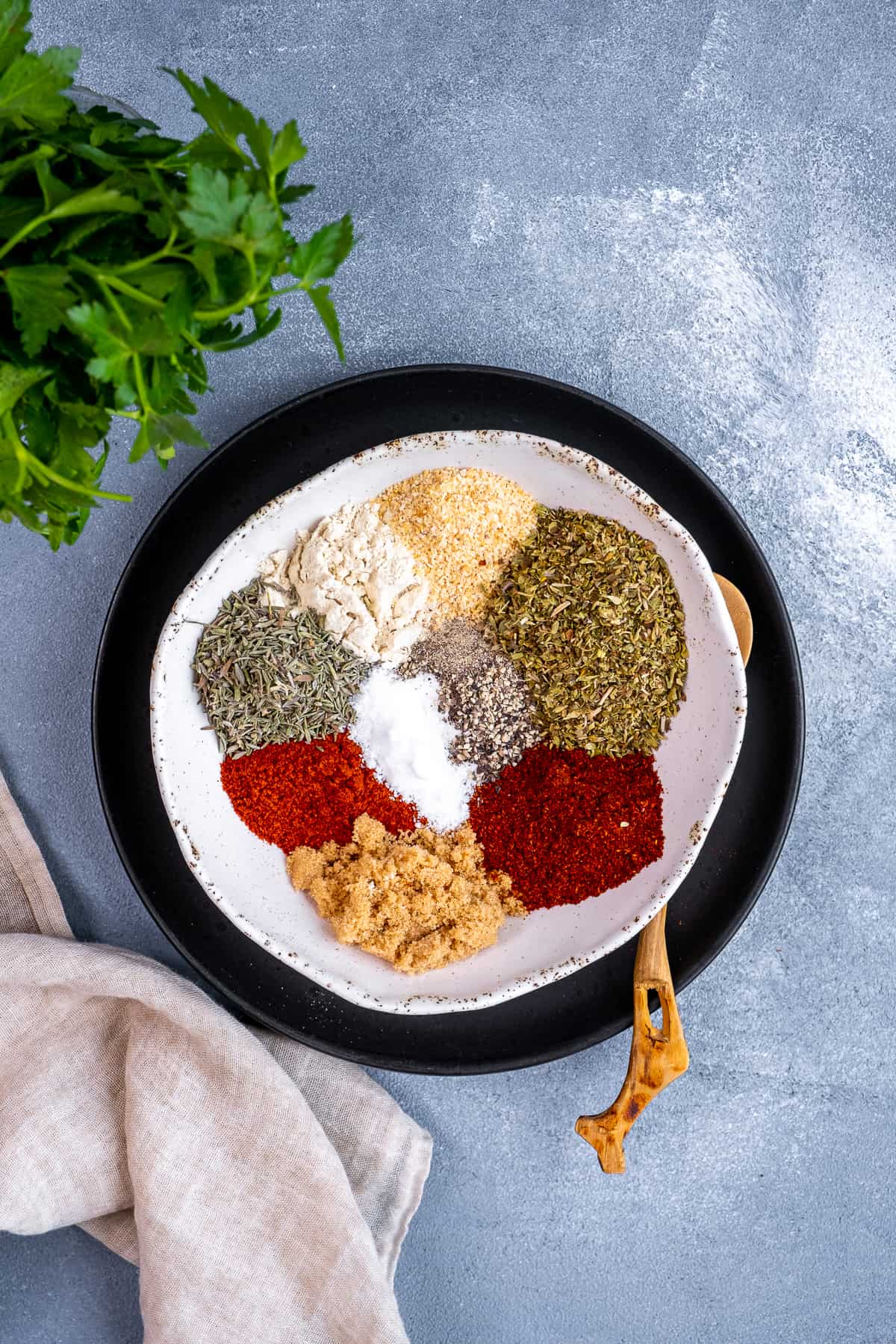 辣椒粉、辣椒粉、牛至、百里香、大蒜粒、洋葱粉等香料,放在一个黑色盘子里的小碗里。