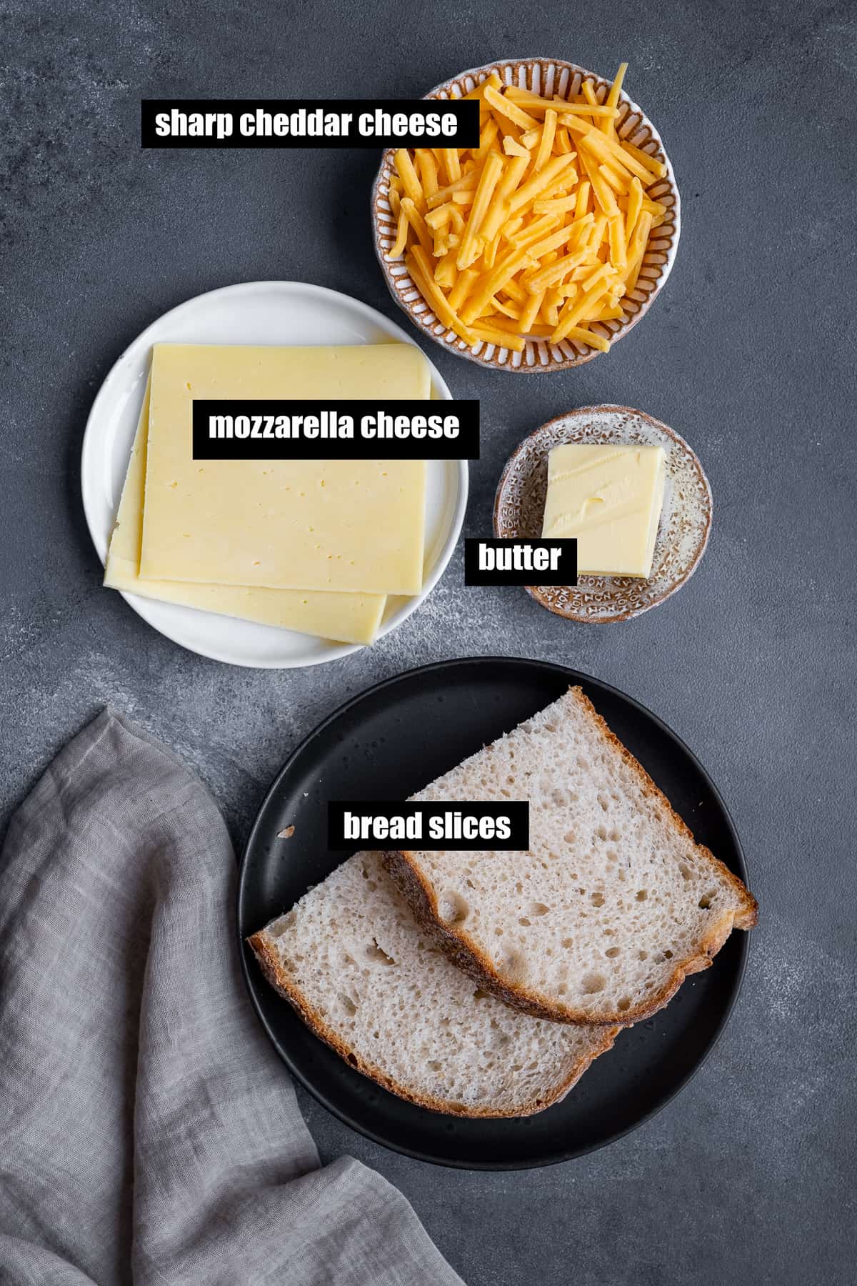 奶酪片，奶酪丝，黄油和面包片在黑暗的背景上。